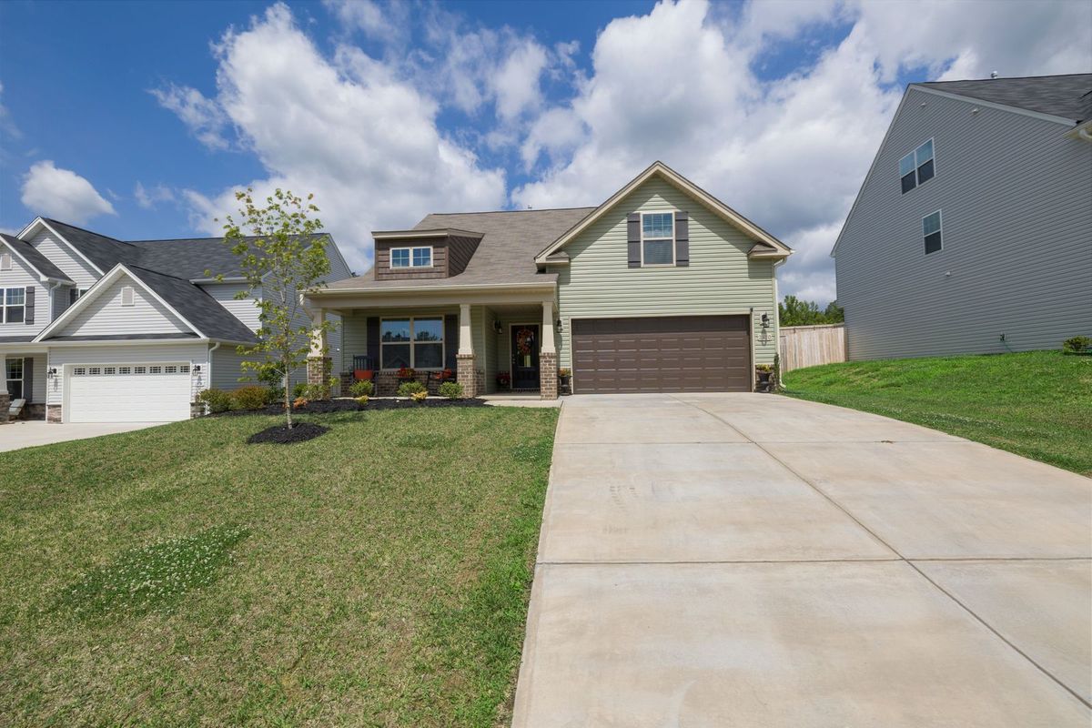 A single-storey home with a brown double garage door at the end of a long driveway