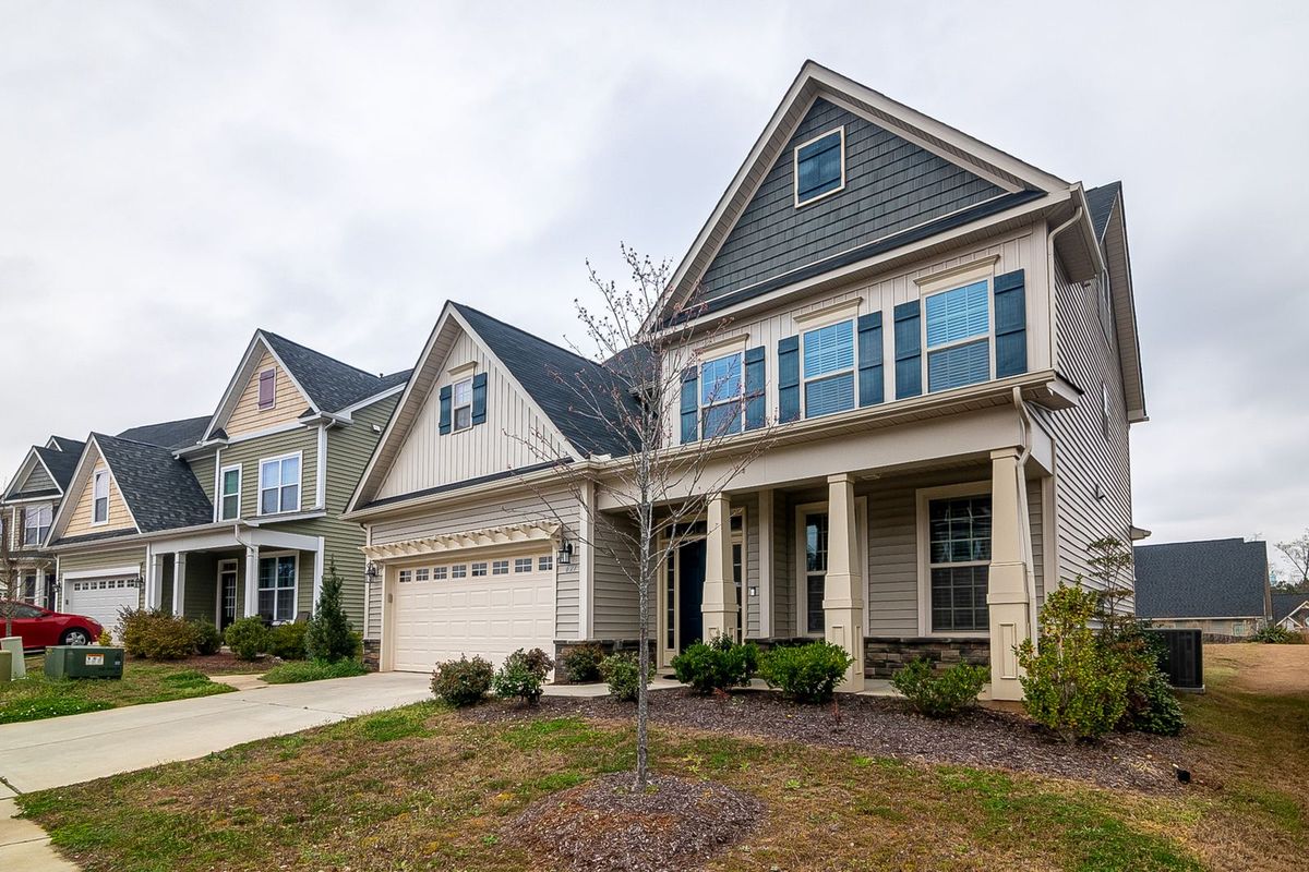 A row of two-storey homes in a subdivision, each with an attached garage and driveway